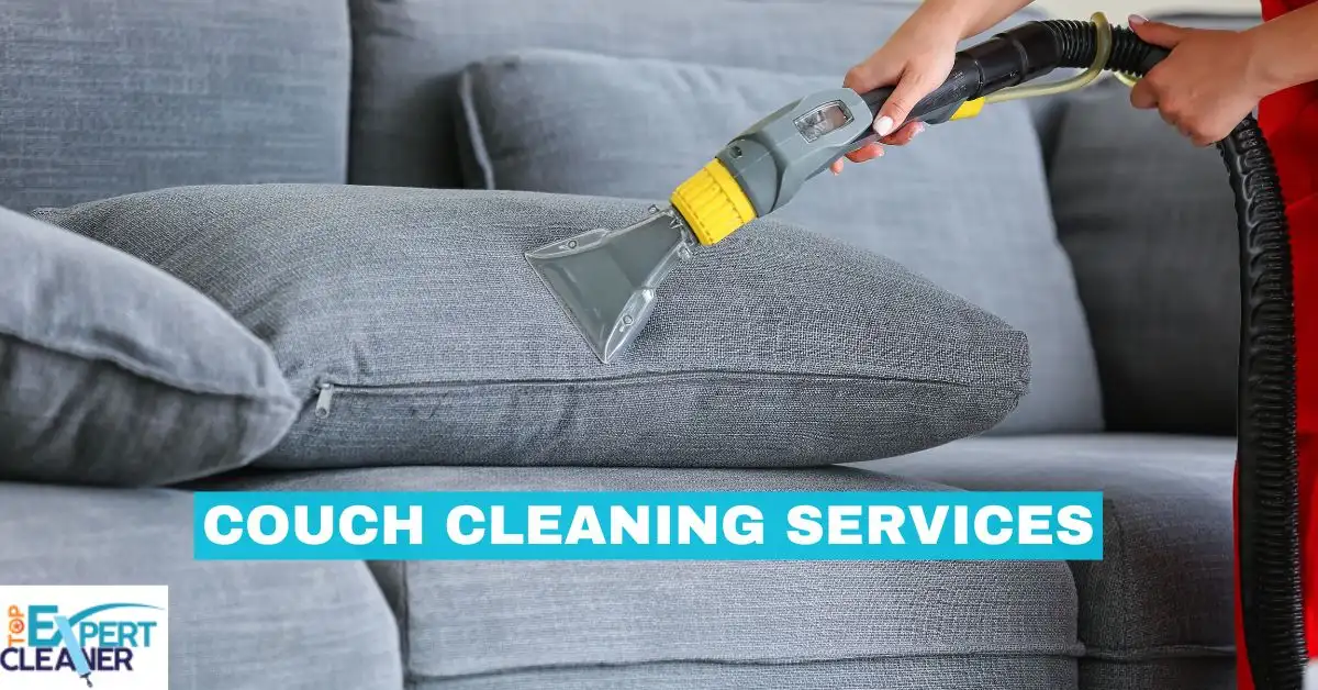 A close-up shot of a professional cleaning tool being used on a grey fabric couch, with the text "COUCH CLEANING SERVICES" overlaid. A hand in a red sleeve is visible operating the tool.