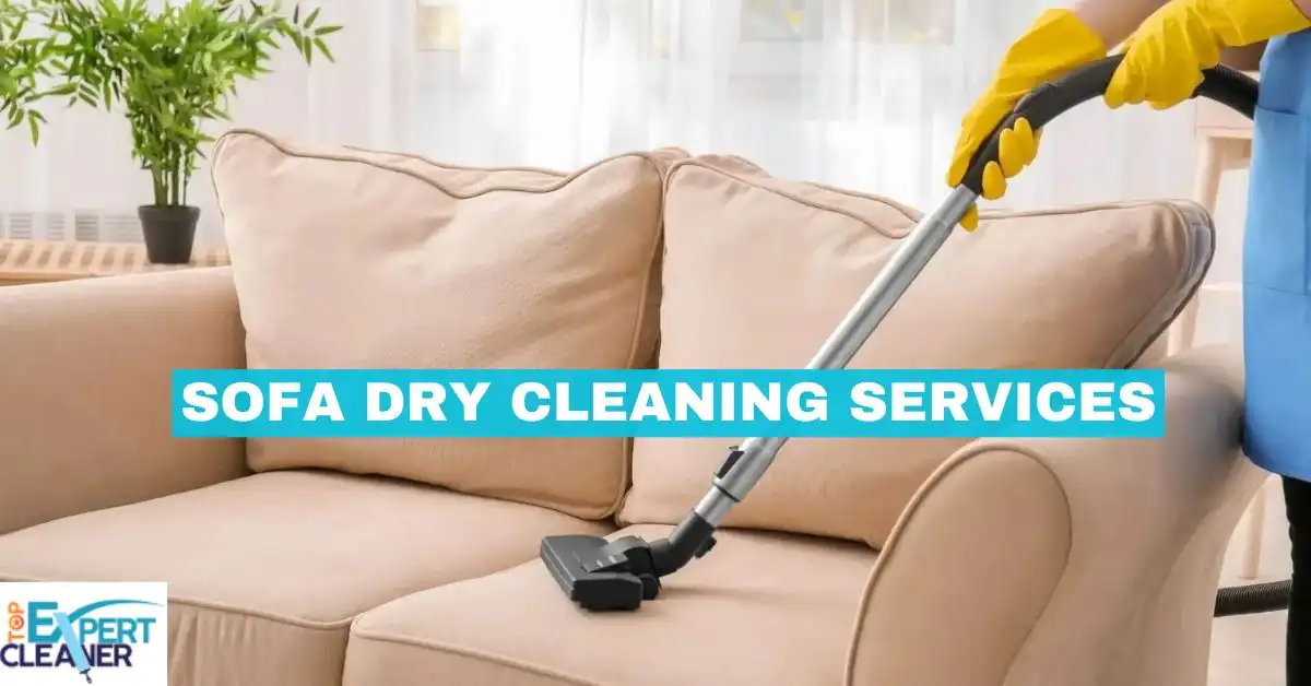 A close-up view of a beige sofa being dry cleaned with a specialized vacuum attachment. A hand wearing a yellow glove guides the cleaning tool. The text "SOFA DRY CLEANING SERVICES" is overlaid in the center.